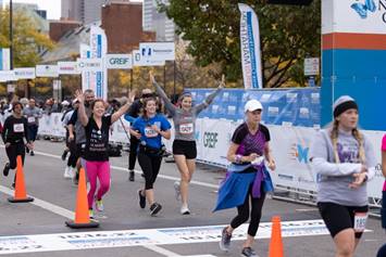 A group of runners enthusiastically cross the line at the marathon event
