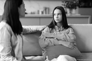 mother and daughter are talking seriously on a couch