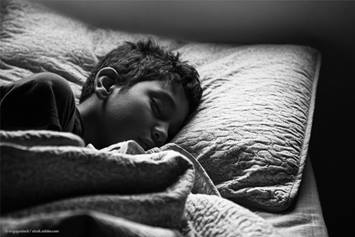 young boy sleeping in his bed covered up by a blanket