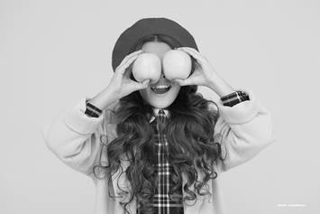 Girls holding two apples over her eyes