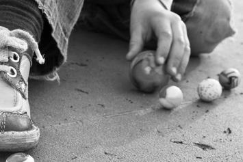 Child's Feet Playing Marbles on Pavement