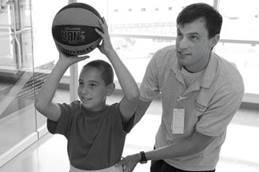 Young rehab patient shooting hoops with a therapist