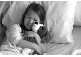 Young Girl in Hospital Bed with Stuffed Animal