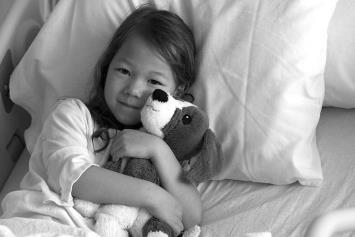Young Girl in Hospital Bed with Stuffed Animal